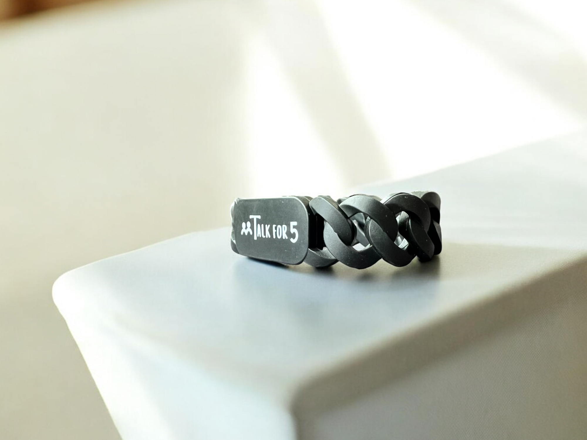 Black chain bracelet with 'Talk for 5' tag on a white surface, perfect for corporates, organizations and schools