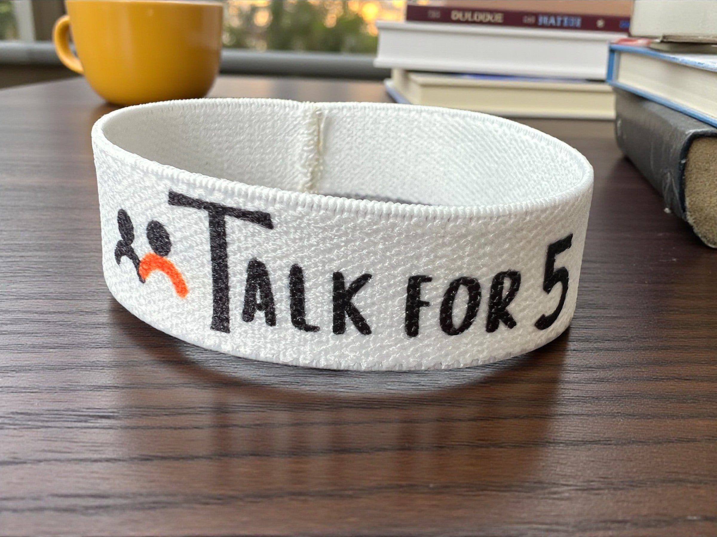 White bracelet with a Talk for 5 logo, designed to support community wellbeing and mental health awareness in Canada